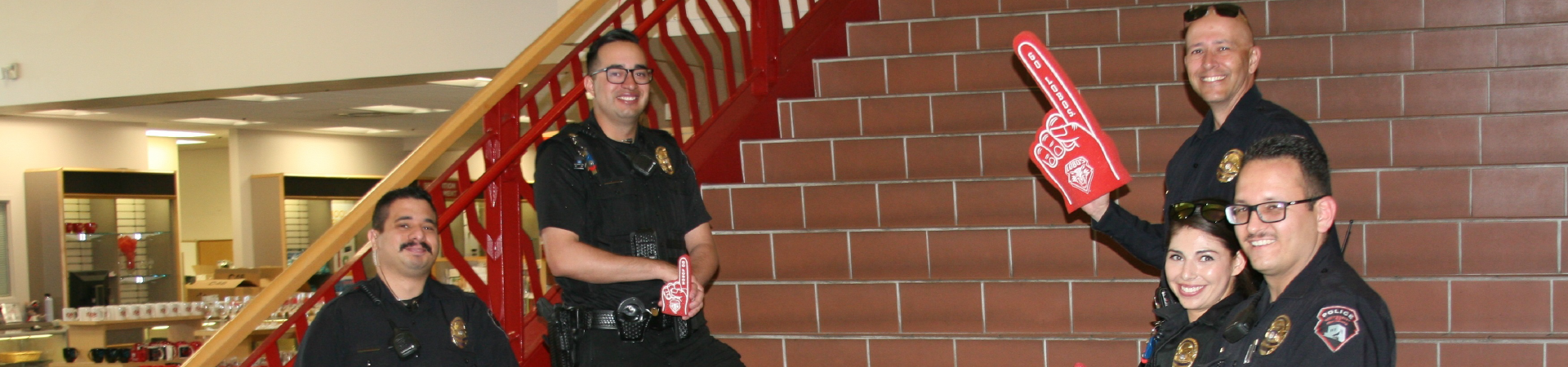 Officers smile, posing on stairs inside bookstore